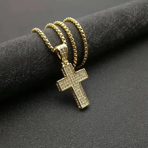Macro detail of gold-plated cross pendant with sparkling rhinestones on box chain