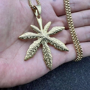 Gros plan détaillé d'un pendentif feuille d'érable dorée avec nervures dans la main