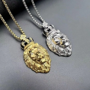 Détail des pendentifs tête de lion avec couronne en or et argent sertis de strass blancs