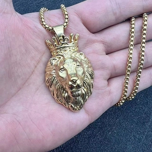 Gros plan détaillé d'un pendentif tête de lion couronné plaqué or tenu à la main