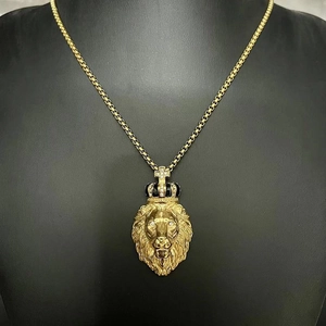 Détail du pendentif tête de lion doré avec couronne en strass sur une chaîne box