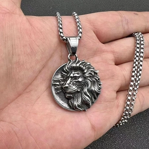 Gros plan du collier pendentif lion argenté avec chaîne maille vénitienne à la main