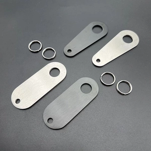 Close-up of titanium steel motorcycle bell tags in brushed silver and matte black finish