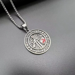 Macro shot of Knights Templar cross pendant with red enamel on textured grey leather background