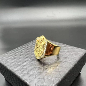 Dettaglio dell'anello con sigillo dorato con motivo a scudo e strass scintillanti