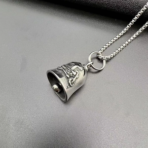 Detailed close-up of antique silver motorcycle bell pendant with biker lucky cross