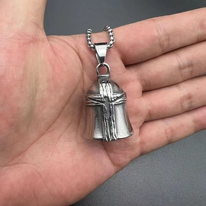 Close-up of vintage steel biker bell pendant with embossed cross and rugged metal chain