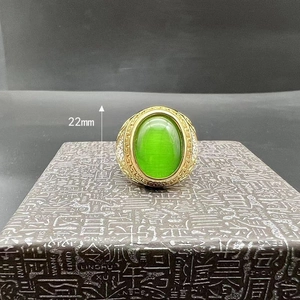 Detail of 22mm gold hip hop ring featuring a green cat eye stone and cubic zirconia