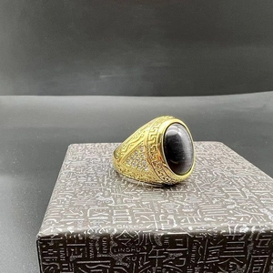Detail of gold-plated stainless steel ring with cat eye stone and Greek fret pattern