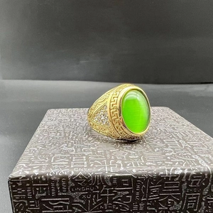 Detail of gold-plated ring featuring an oval green cat-eye stone and side carvings