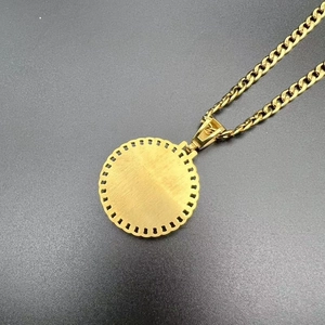 Détail d'une chaîne maille gourmette dorée et pendentif rond brossé aux bords ajourés
