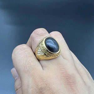 Detail of gold-plated stainless steel men's ring with black cat eye stone and Greek key patterns