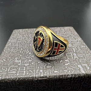 Macro shot of gold Templar shield ring with red enamel cross and decorative white crystals