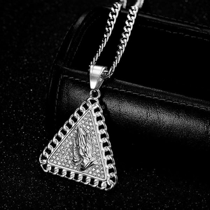 Macro shot of silver praying hands triangle pendant with rhinestones and cuban chain