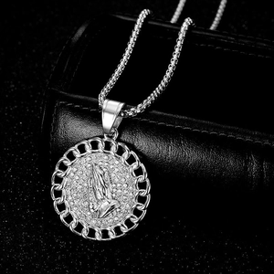 Macro shot of silver hip hop necklace with iced-out praying hands circular pendant