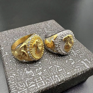 Dettaglio macro degli anelli da uomo con aquila placcati in oro e strass luccicanti