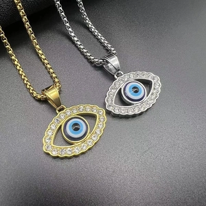 Detail of gold and silver box chains featuring iced-out evil eye pendants with rhinestones