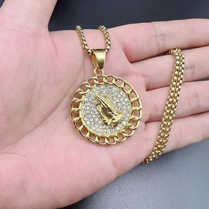Detailed view of a gold-plated prayer hands pendant necklace with sparkling zircon pavé
