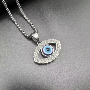 Macro shot of silver hip hop evil eye pendant with blue crystals and square link chain