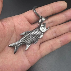 Vintage stainless steel fish-shaped keychain opener held in hand with scaly texture