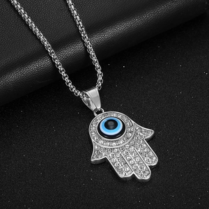 Hamsa Hand pendant necklace with Evil Eye and clear rhinestones on black background