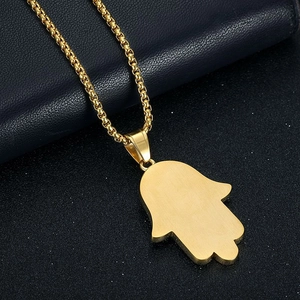 Detailed close-up of golden Hamsa Hand pendant with brushed metal texture on box chain