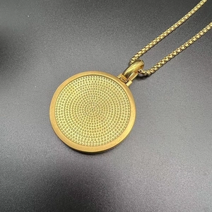 Macro detail of golden circular pendant with textured dots and sleek box chain necklace