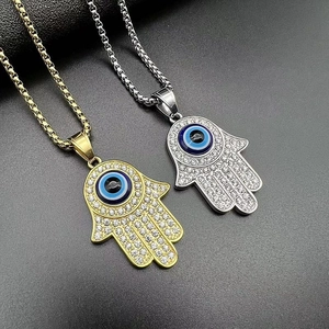 Detail of gold and silver Hamsa Hand pendants with blue evil eye and sparkling crystals
