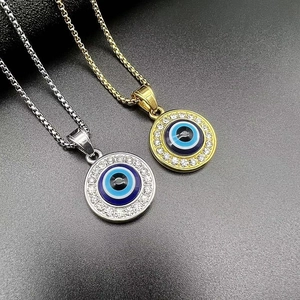 Detail of gold and silver Evil Eye pendants with crystals on black matte background