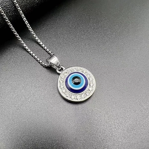 Macro shot of silver Evil Eye pendant necklace with blue eye and sparkling crystals