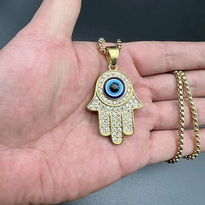 Detailed close-up of gold Hamsa pendant with Evil Eye and pavé crystals on a box chain
