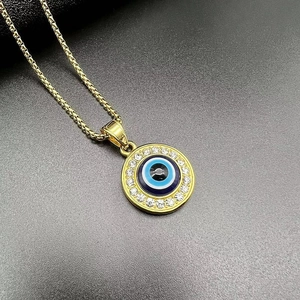 Detailed macro view of gold evil eye pendant with box chain on dark textured surface