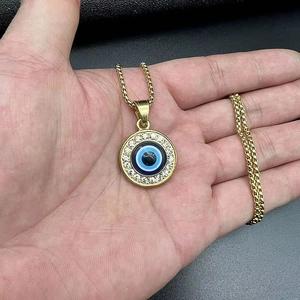 Close-up of golden Evil Eye pendant with sparkling rhinestones held in hand