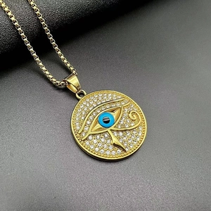 Macro detail of gold Eye of Horus pendant with blue pupil and white cubic zirconia crystals
