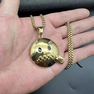Close-up of a gold-plated Shut Up emoji pendant with a box chain on black leather