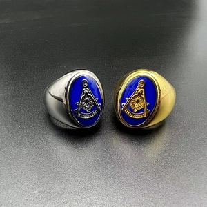 Detail of Masonic rings in gold and silver finish with blue enamel emblem on a gray surface