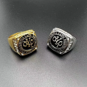 Dettaglio di anelli con sigillo in oro e argento con emblemi AKA e strass trasparenti
