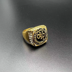 Dettaglio macro dell'anello sigillo dorato con logo AKA e diamanti sui lati