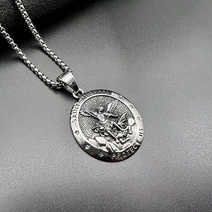 Gros plan détaillé du pendentif Saint Michel avec texte gravé sur métal argenté vieilli