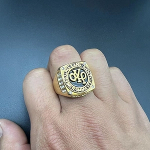 Vista dettagliata di un anello a sigillo dorato con lettere greche e strass sui lati