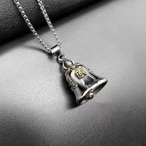Close-up of titanium steel motorcycle bell pendant with gold Sanskrit mantra detail