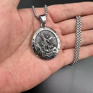 Vue rapprochée du collier pendentif Saint Michel en acier titane vintage dans la main