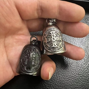 Detail showing polished black and silver St. Benedict bell pendants with religious engraving