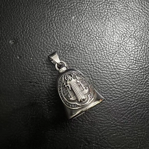Macro view of St. Benedict vintage silver steel bell pendant with religious engravings