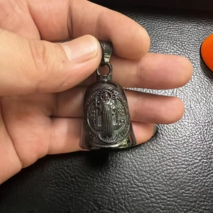 Close-up of black polished St. Benedict metal bell pendant with religious engraving