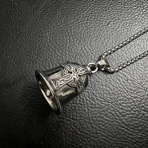 Macro view of vintage titanium steel Viking cross bell pendant on black leather