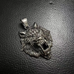 Detailed close-up of a vintage silver viking wolf head pendant on black leather