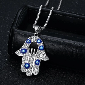 Pendentif Main de Fatma glacé avec œil bleu maléfique sur chaîne argentée style hip hop