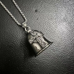 Macro shot of silver Viking cross guardian bell pendant on black leather surface