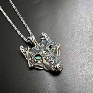 Detailed close-up of Viking wolf pendant with green gemstone eyes and Celtic knotwork